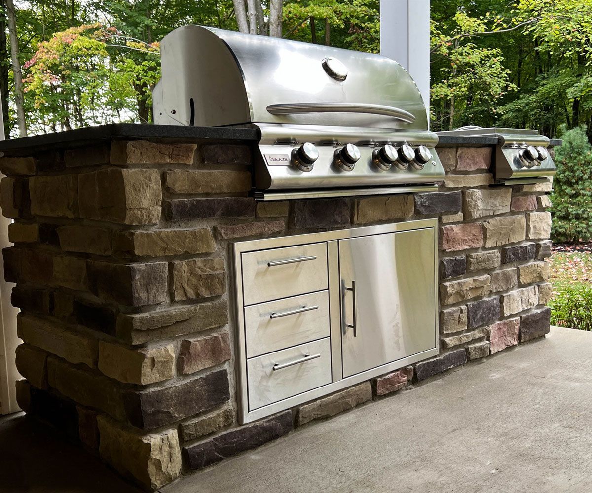 Dining outside on Medina, Ohio backyard patio with outdoor kitchen and gas grill designed and installed by Cleveland area landscape contractor Chidsey Landscape and Design