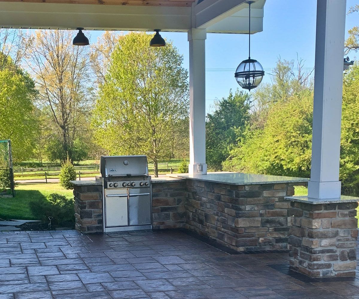 Custom outdoor kitchen covered by pavilion on Hudson, Ohio paver block patio by Chidsey Landscape & Design.