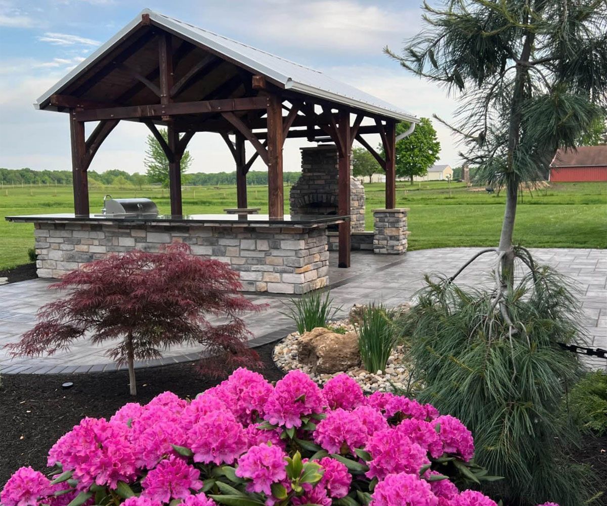 Hudson, OH outdoor living landscape design with all weather pavilion, paving stone patio, and garden beds with plantings.