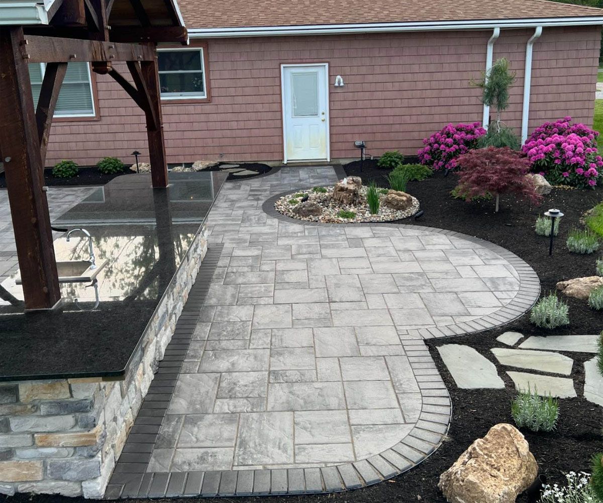 Bath, OH outdoor living spaces with pavilion, outdoor kitchen, paving stone patio, and water feature natural stone bubbler.