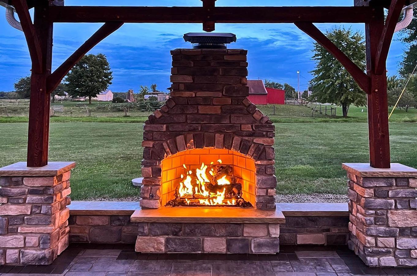 Outdoor gas fireplace with stone veneer under Northeast Ohio backyard pavilion.