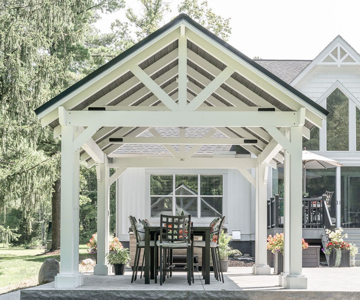 White vinyl backyard pavilion with slat roof covering outdoor kitchen area of Medina County home.