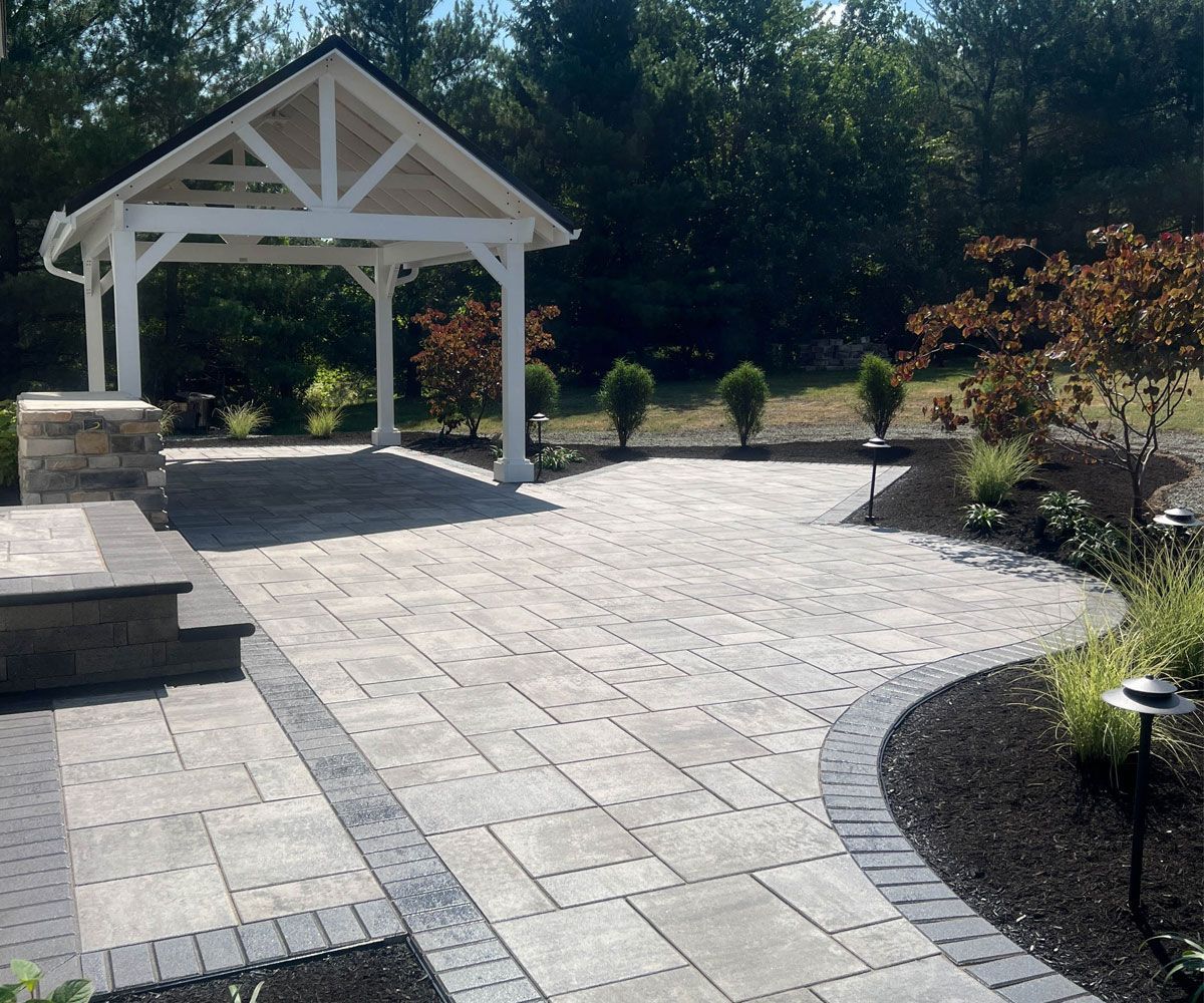Copley, OH backyard with new paver patio installation with landscape lighting and plantings by Chidsey Landscape & Design