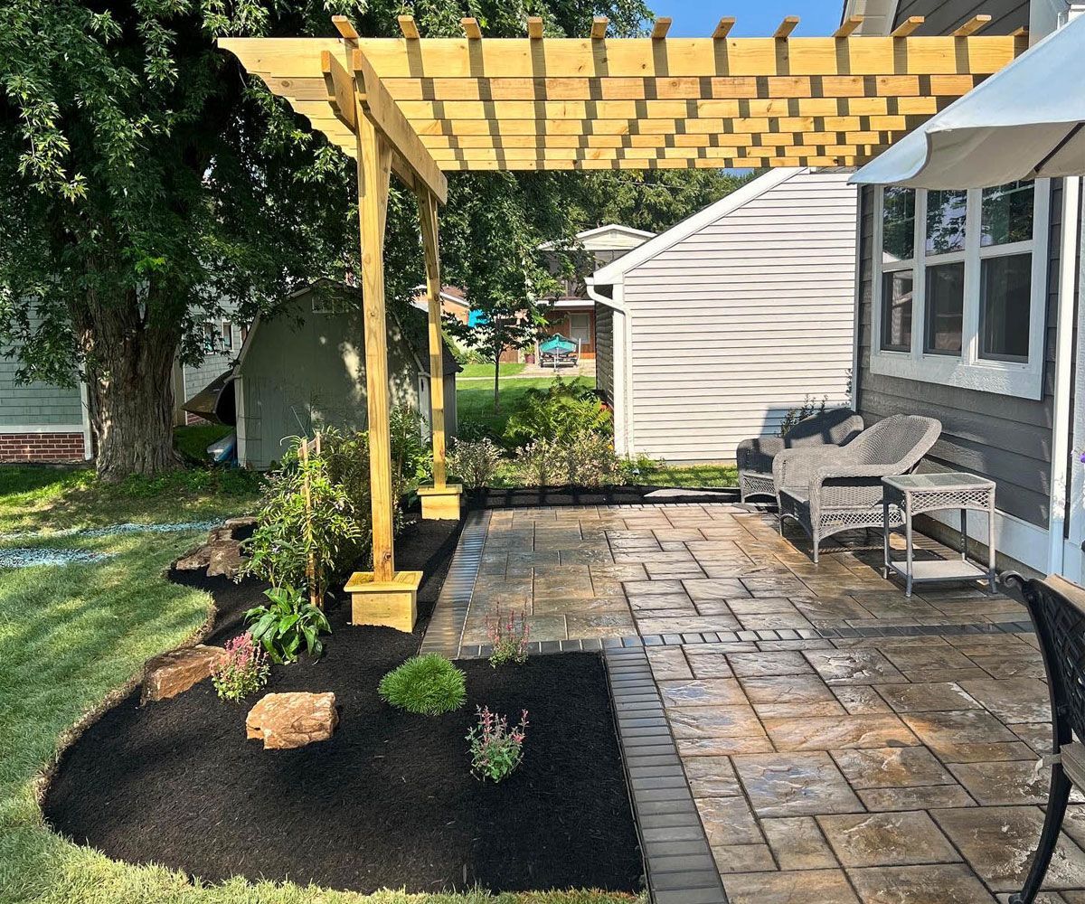 Geometric pattern paver patio in Copley, Ohio backyard with pergola and outdoor furniture designed and installed by Chidsey Landscape & Design