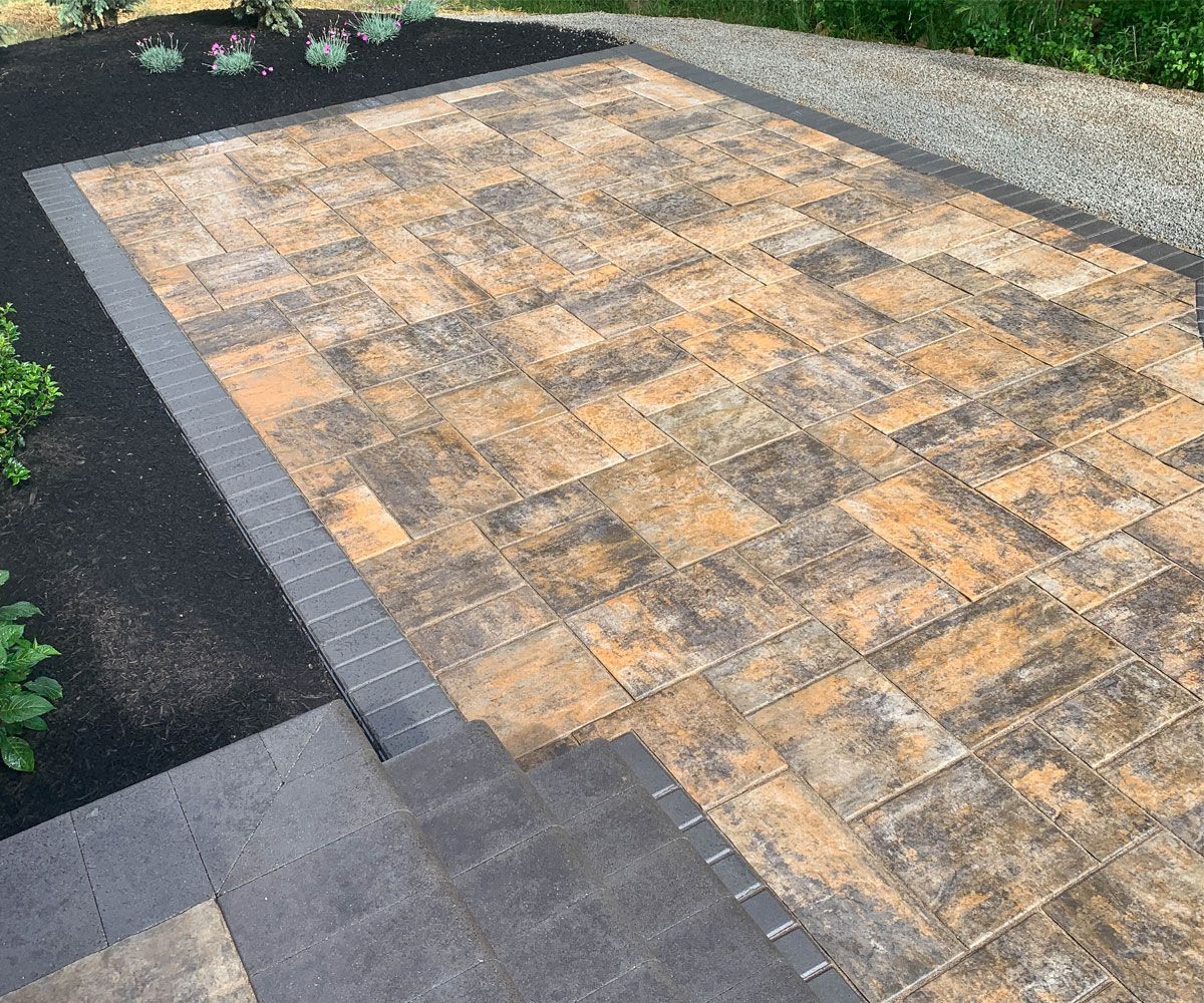 Hardscape paving stone patio installed with Unilock paver stones and black soldier course border in Bath, Ohio backyard.