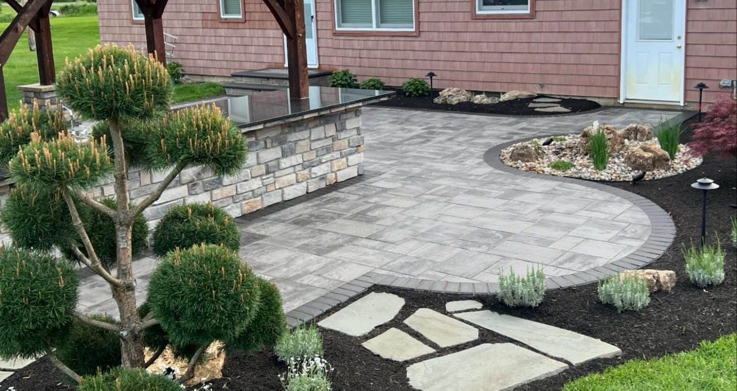 Customer outdoor living paver patio hardscape with pavilion and outdoor kitchen in Medina backyard.