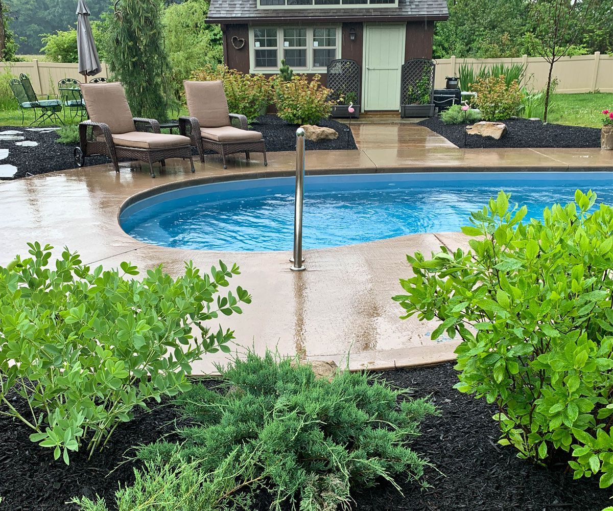 Natural evergreens and shrubs create a softscape privacy screen for a Lorain County, OH pool.