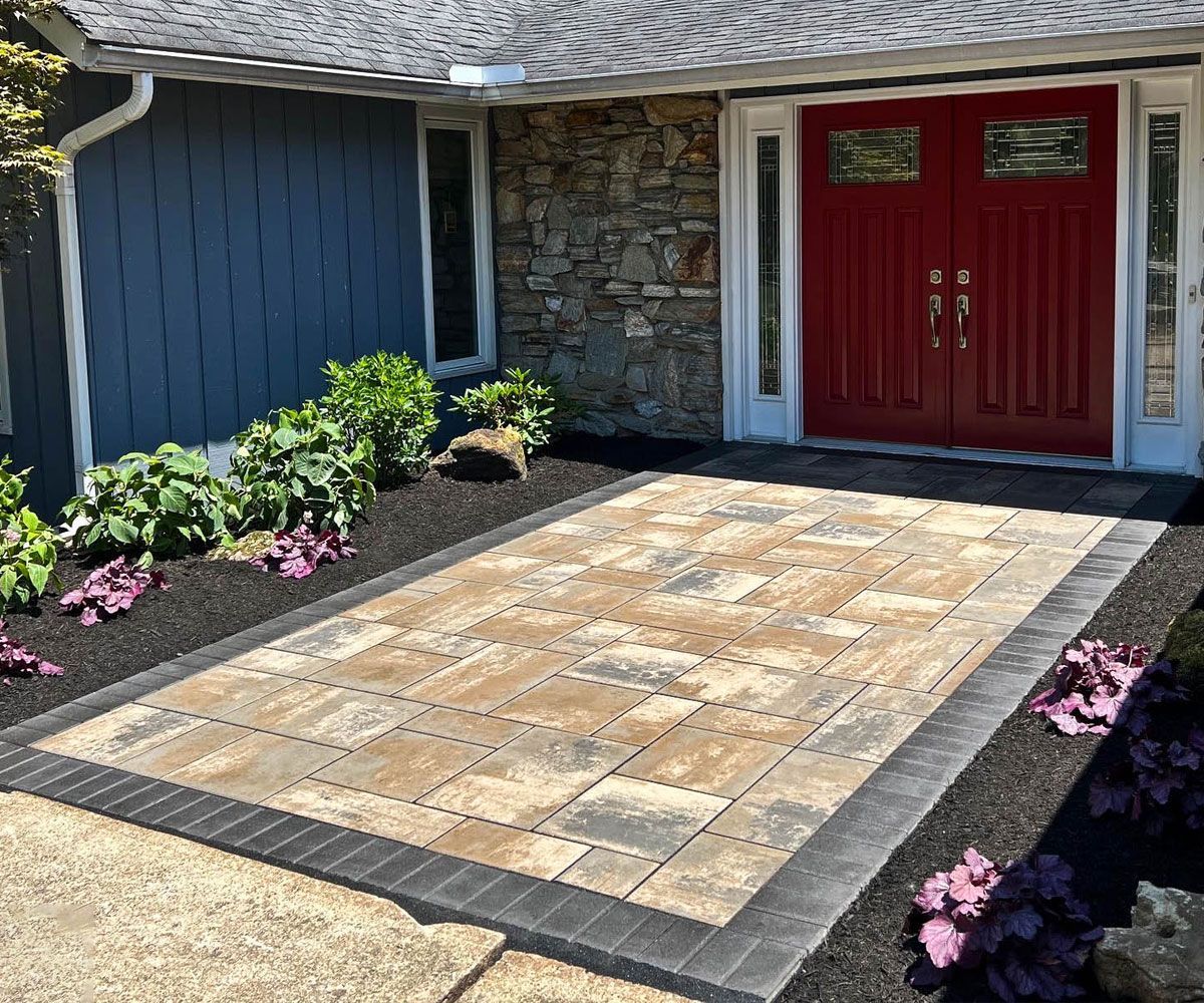 Large slab Unilock paver front entrance of Lorain County home with dark paving stone border by Chidsey Landscape & Design