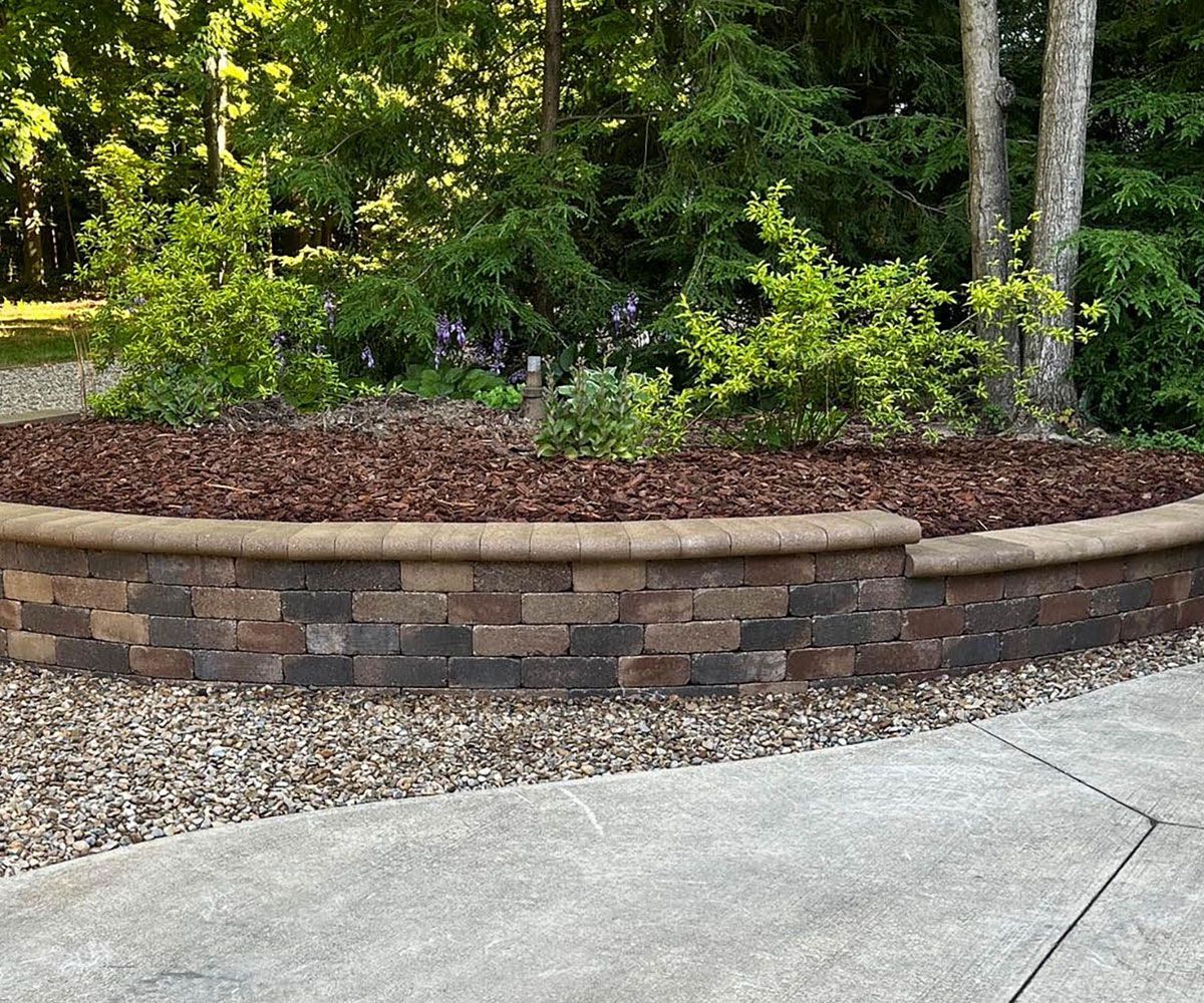 Retaining wall with garden plantings at front of Bath, Ohio home near driveway.