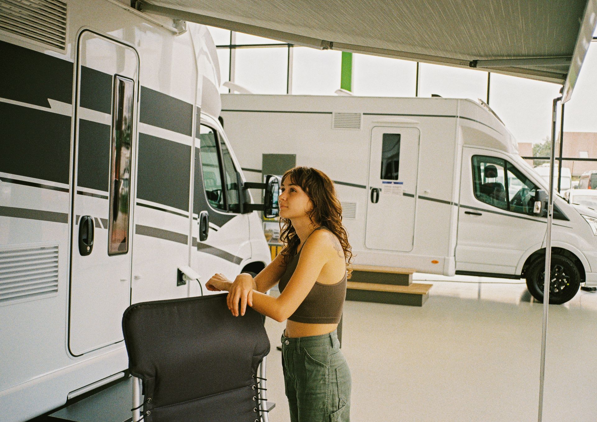 Woman standing next to a camping van, looking up. Indoors.