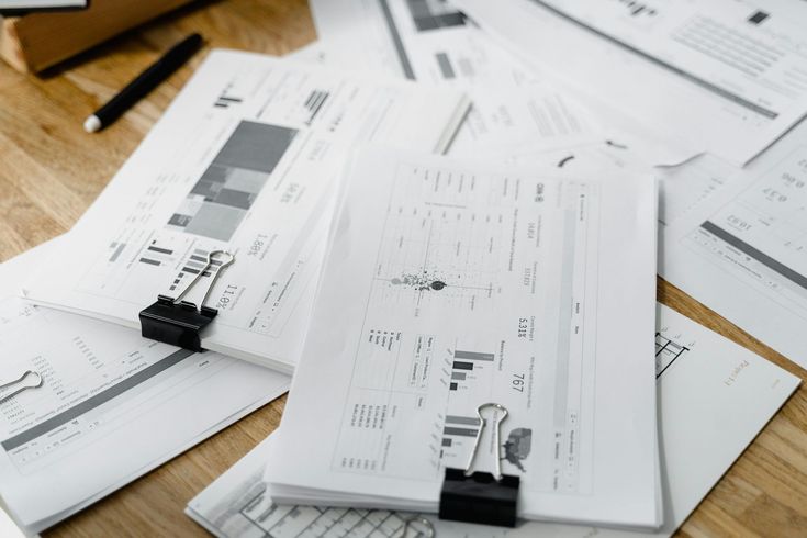A bunch of papers are sitting on a wooden table.