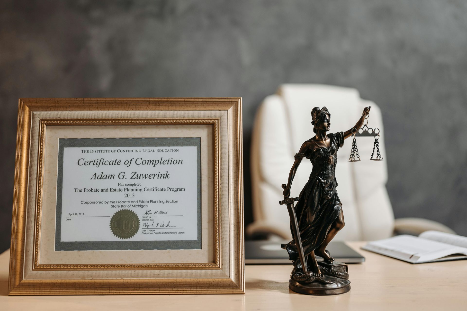 A statue of justice is sitting on a desk next to a certificate of completion.