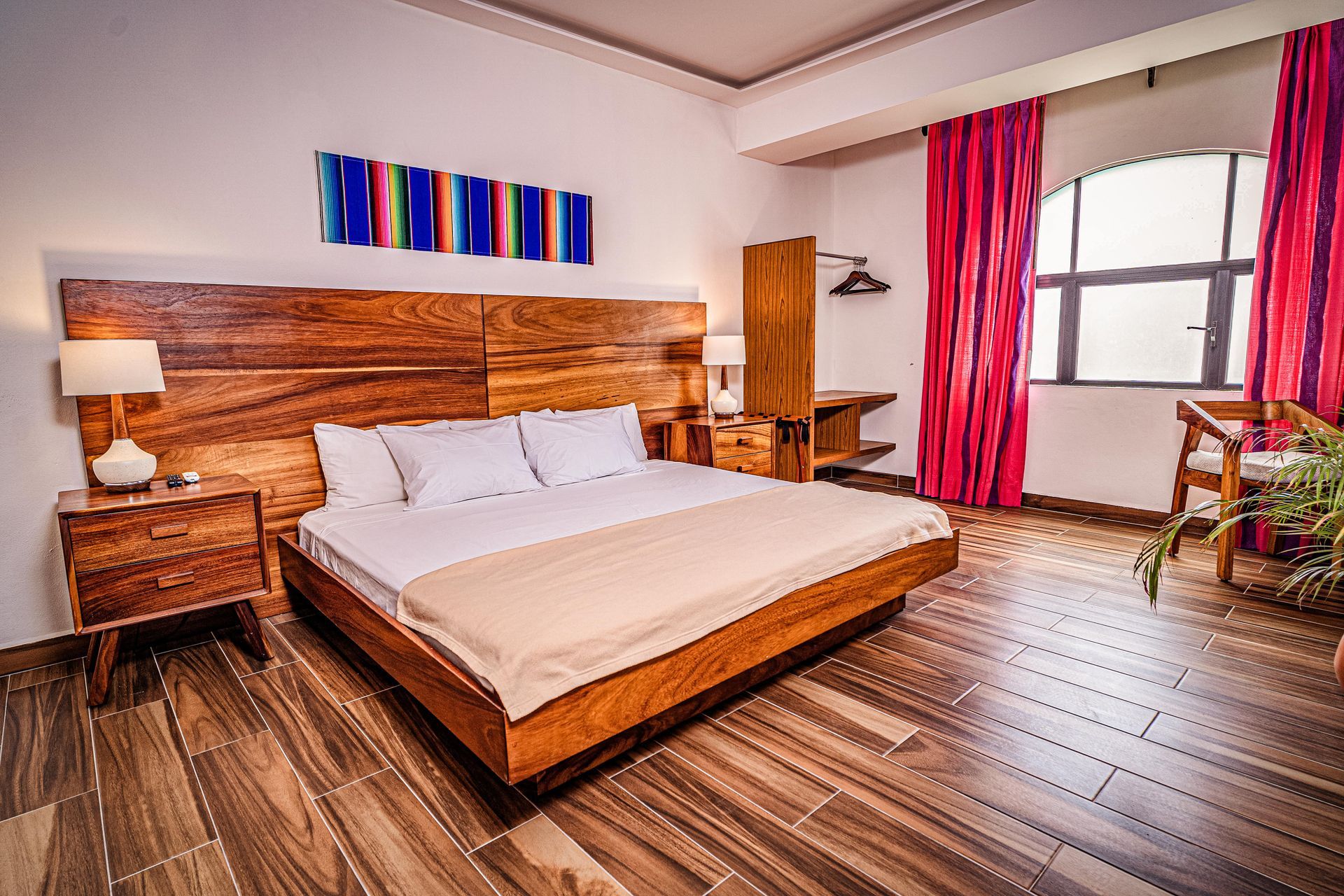 A hotel room with a king size bed and a wooden headboard at nomads party the most comfy hotel in cancun.