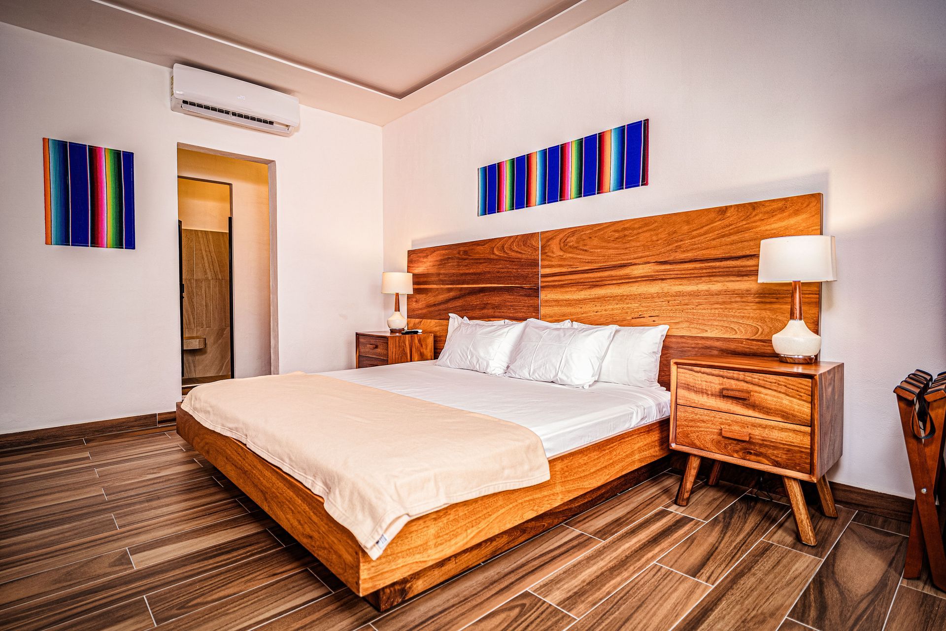 A bedroom with a king size bed , nightstands , lamps and a wooden headboard at nomads the party hostel in cancun.