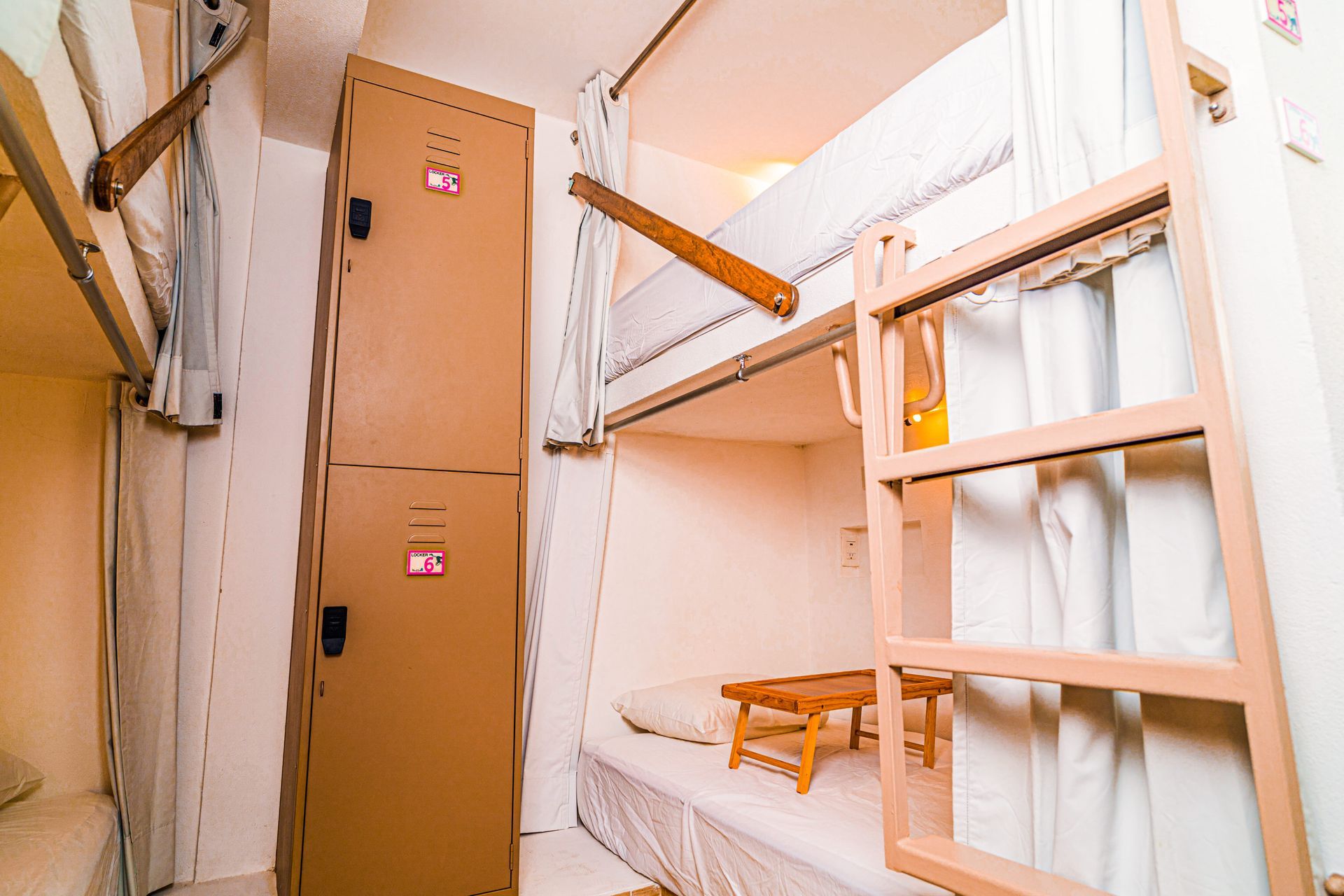 A bunk bed with a ladder and a locker in a room at nomads party the greatest hostel in cancun.