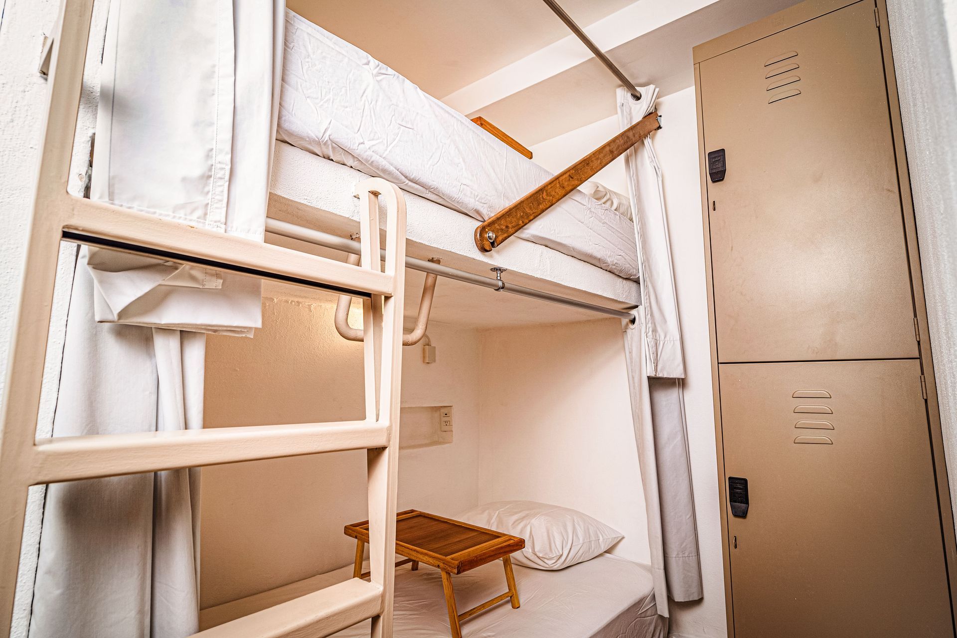 A bunk bed with a ladder in a room with lockers.