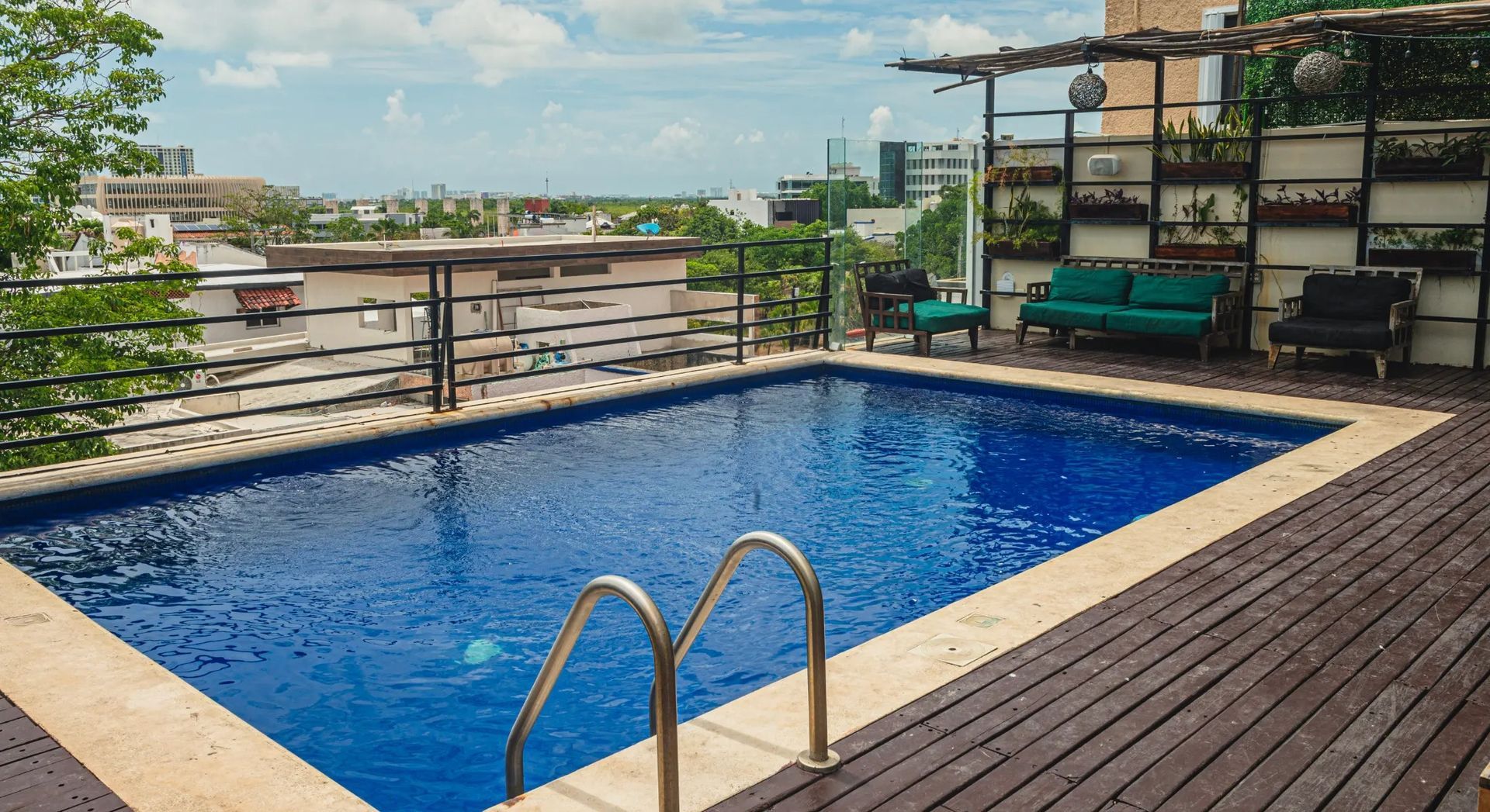 A large swimming pool is sitting on top of a wooden deck in nomads the best hostel in cancun downtown.