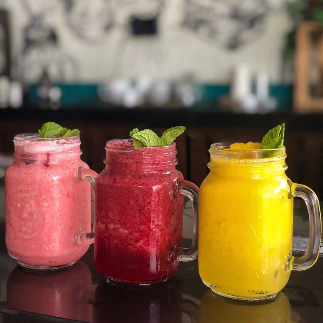 Three different colored smoothies in mason jars on a table