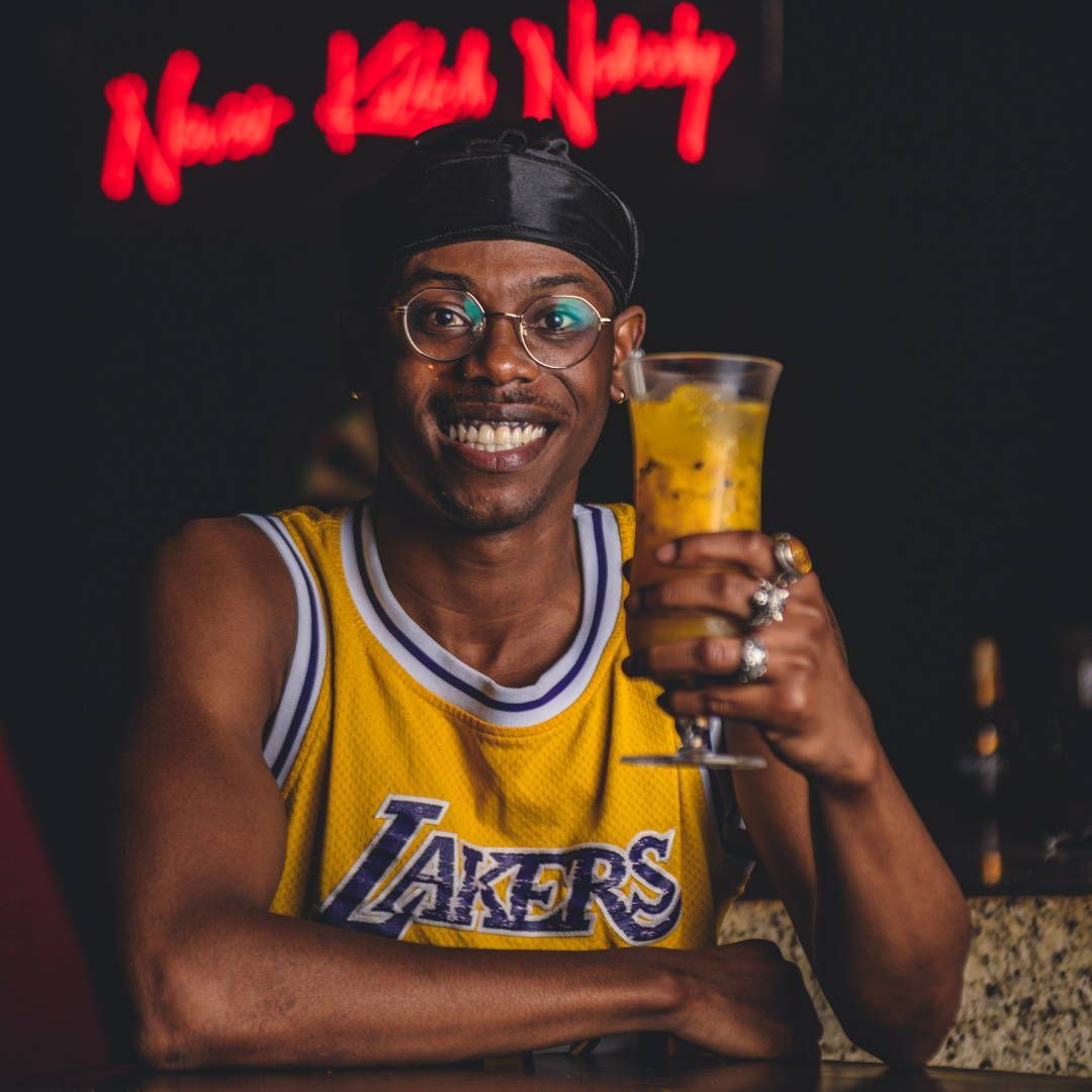 A man wearing a lakers jersey is holding a drink