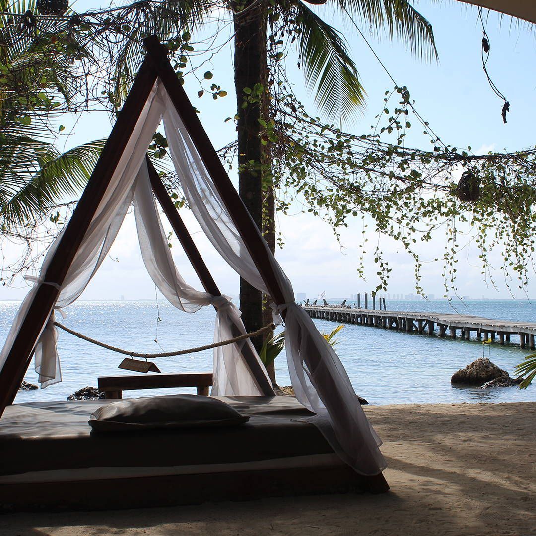 A canopy bed on the beach with a view of the ocean