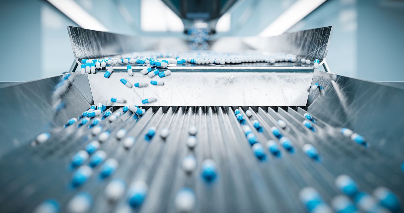 A conveyor belt filled with blue and white pills in a factory.