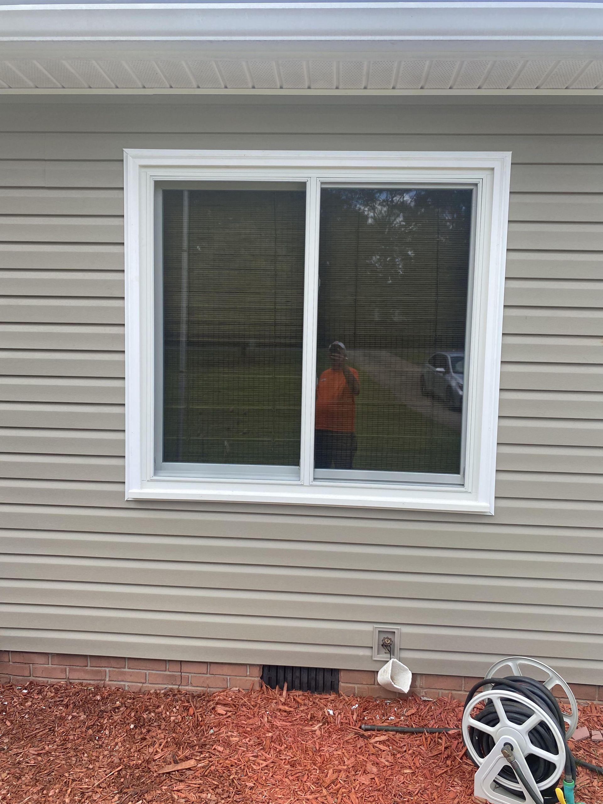 A house with a window and a hose on the side of it.