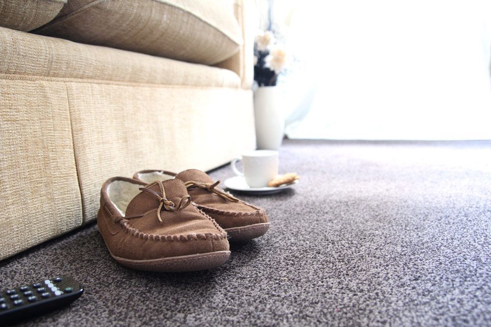 A Pair Of Shoes And A Remote Control On The Floor In A Living Room — Encore Carpet Professionals in Parkwood, QLD