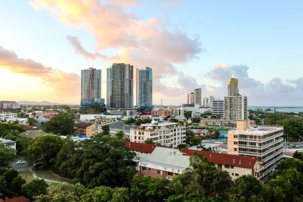 An Aerial View Of A City With Lots Of Buildings And Trees At Sunset — Encore Carpet Professionals in Southport, QLD