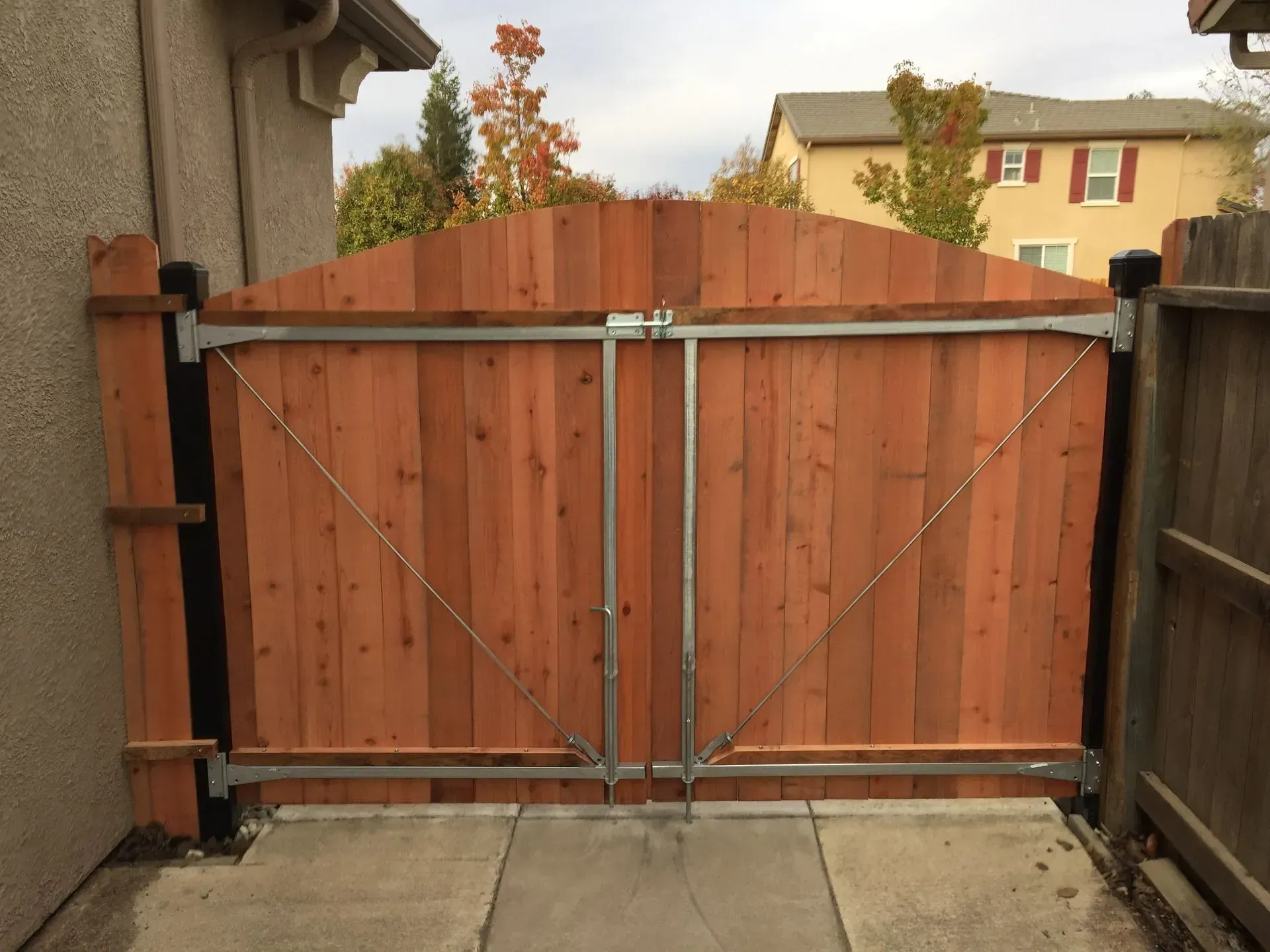 Wooden double gate with metal supports in a paved pathway.