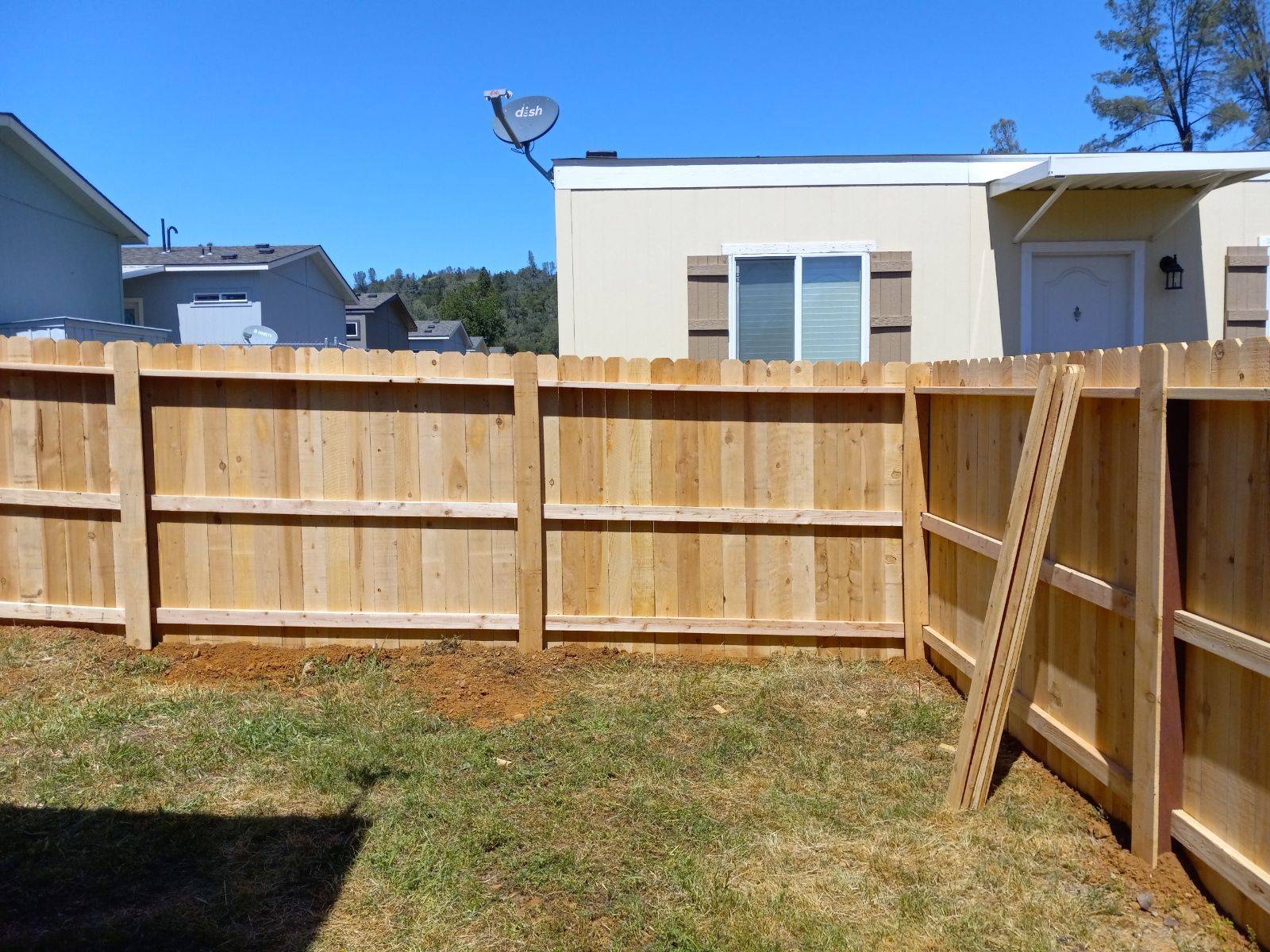 Wooden gate and fence in a backyard, brown wood, sunny day.
