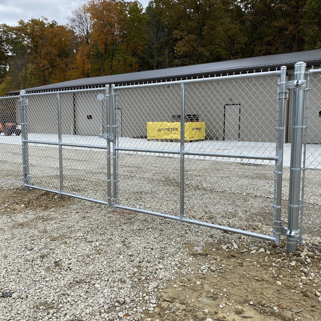 Wooden double gate with wire mesh panels, in a backyard setting.
