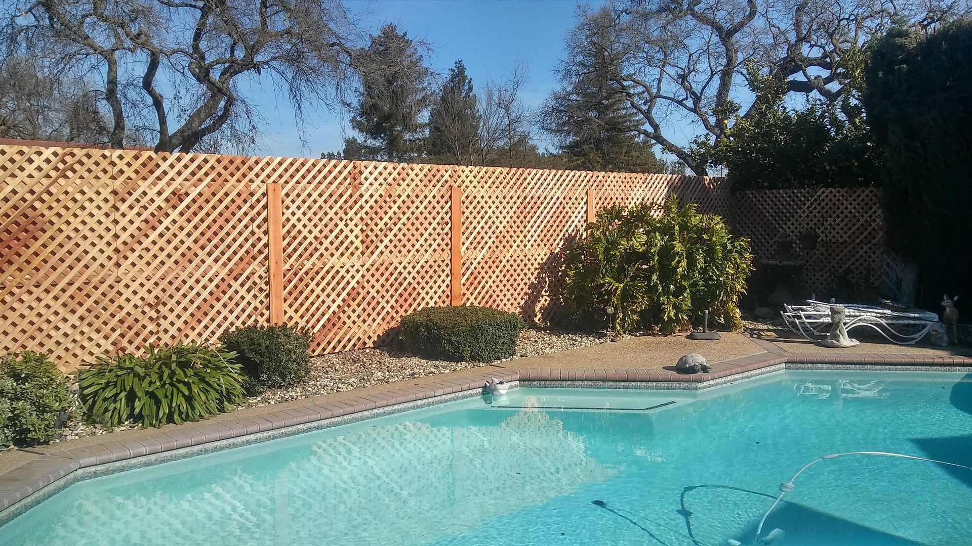 Wooden gate with vertical planks, attached to a wire fence. Autumn trees in the background.