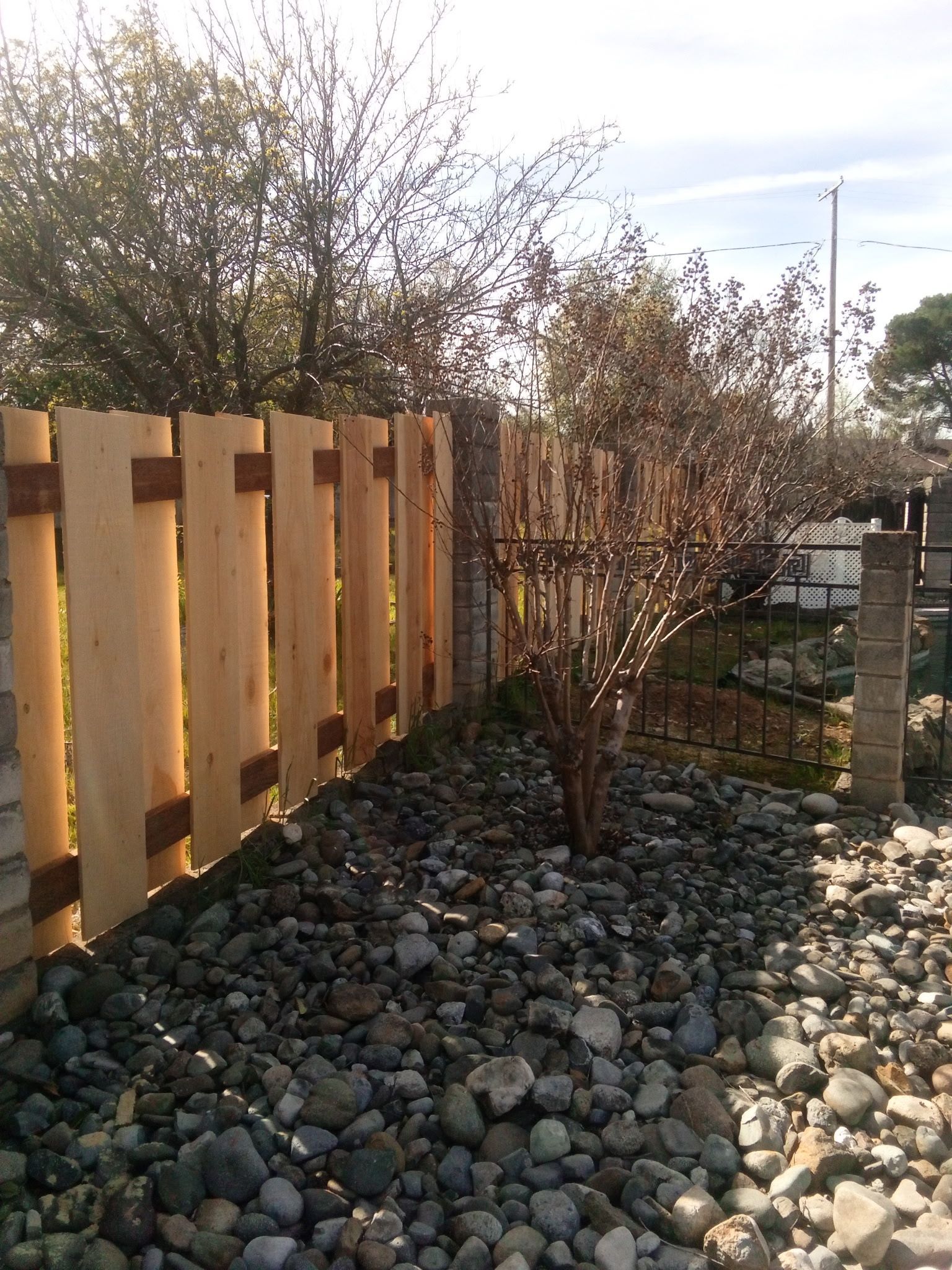 Wooden fence in front of a beige building with a small window and a lamp.