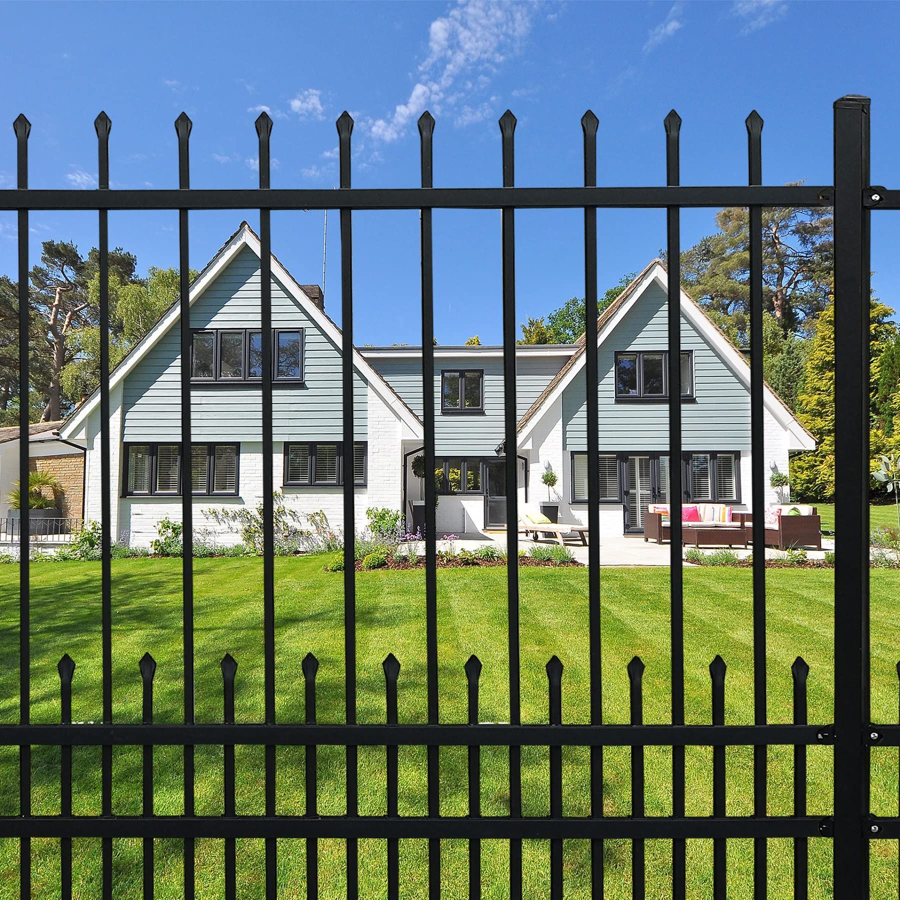 Black metal fence enclosing a patio with French doors, fire pit, and a beige house.