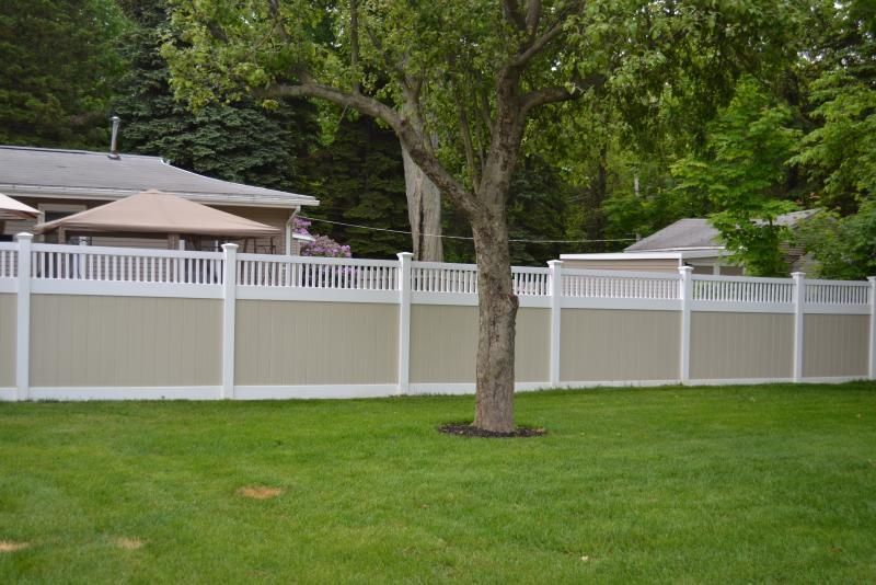 Wooden split-rail fence along a dirt area, with a residential street and houses in the background.