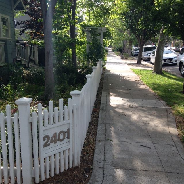 Wooden double gate with metal supports in a paved pathway.