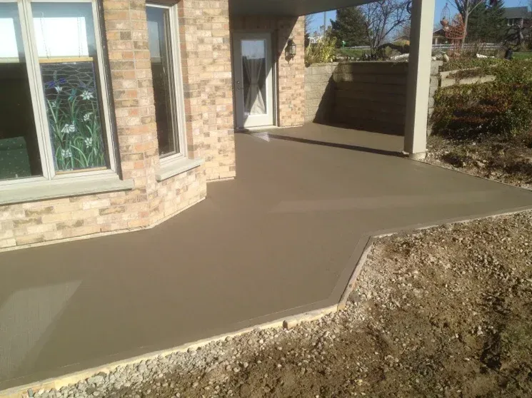 A brick house with a concrete walkway in front of it.