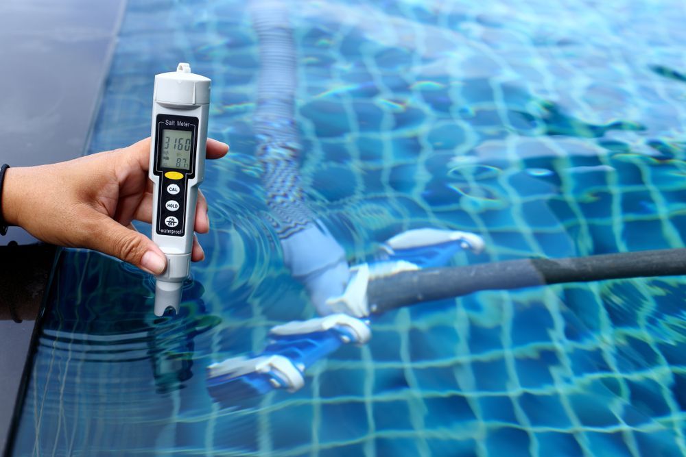 A Person is Holding a Thermometer Over a Swimming Pool — NQ Tropical Pools & Renovations in Cranbrook, QLD
