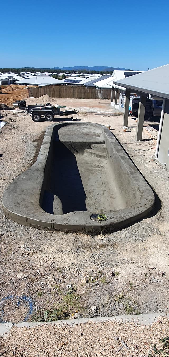 A Large Concrete Pool is Being Built in the Backyard of a House — NQ Tropical Pools & Renovations in Cranbrook, QLD