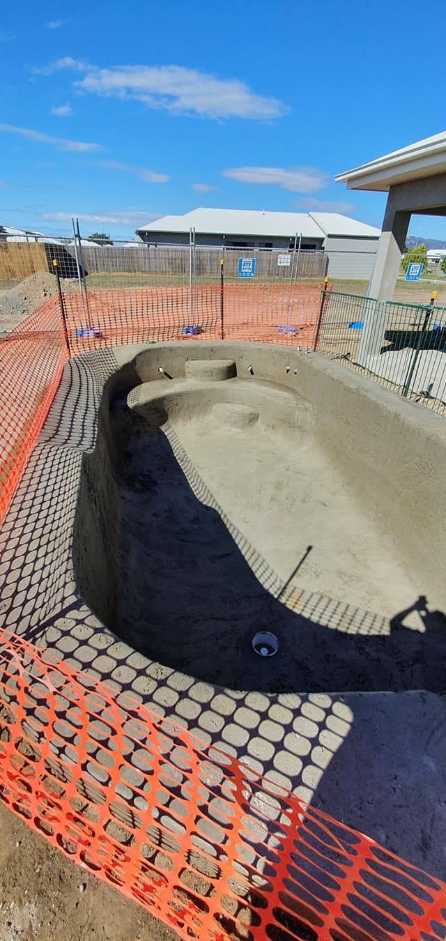 A Swimming Pool is Being Built in the Dirt With a Fence Around It — NQ Tropical Pools & Renovations in Airlie Beach, QLD