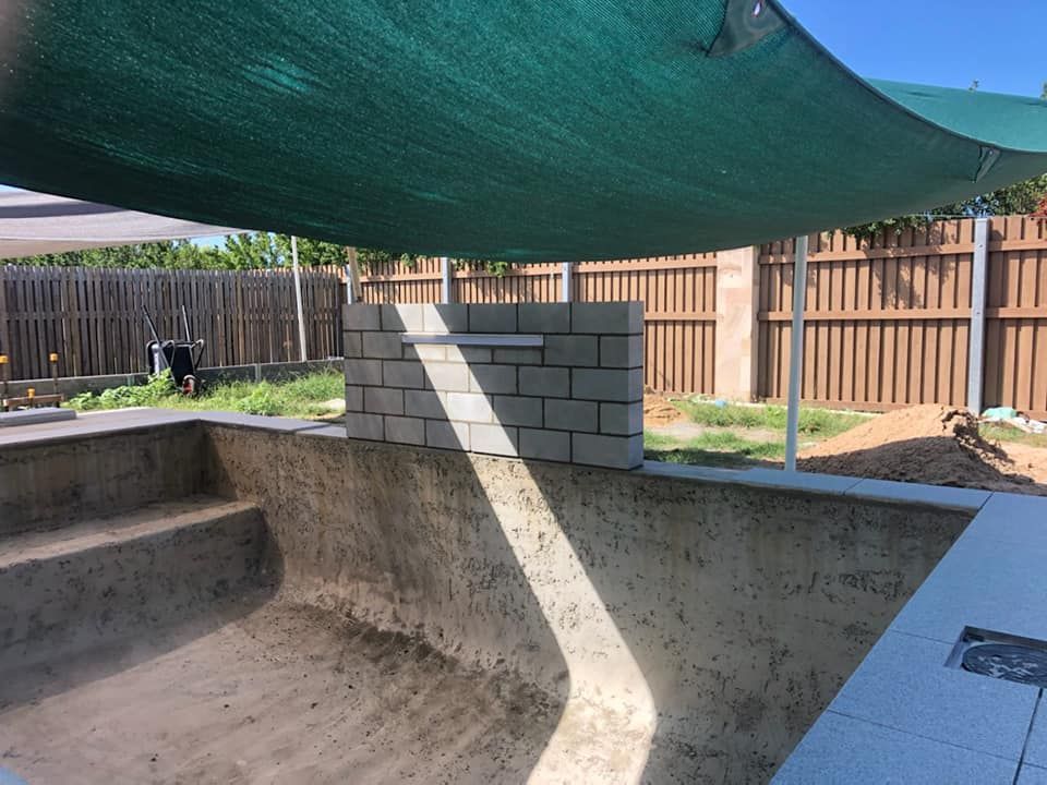 A Swimming Pool is Being Built in a Backyard Under a Green Umbrella — NQ Tropical Pools & Renovations in Burdekin, QLD