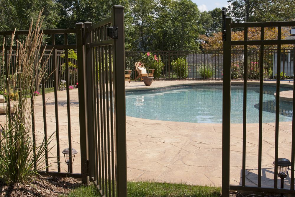A Fence Surrounds a Swimming Pool in a Backyard — NQ Tropical Pools & Renovations in Bowen, QLD