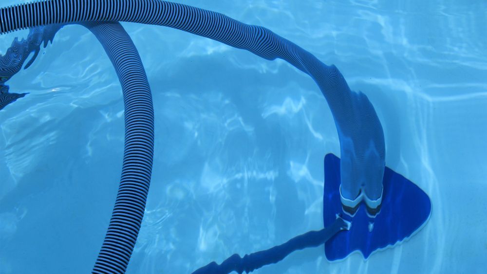 A Hose is Floating in the Water of a Swimming Pool — NQ Tropical Pools & Renovations in Cranbrook, QLD