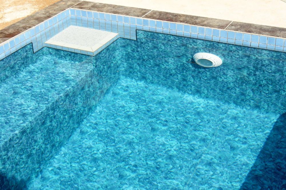 A Swimming Pool Filled With Blue Water and Steps — NQ Tropical Pools & Renovations in Cranbrook, QLD