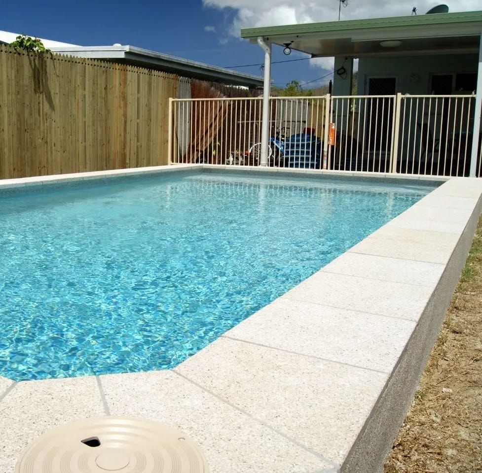 A Swimming Pool With a Wooden Fence Surrounding It — NQ Tropical Pools & Renovations in Cranbrook, QLD