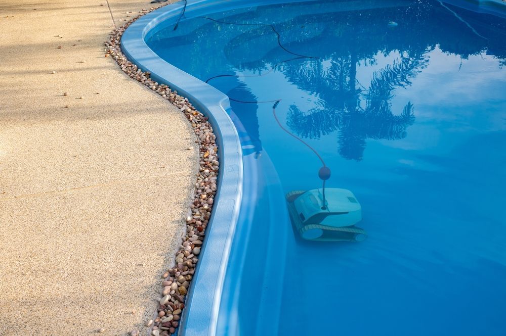A Robotic Pool Cleaner is Sitting in the Middle of a Swimming Pool — NQ Tropical Pools & Renovations in Cranbrook, QLD