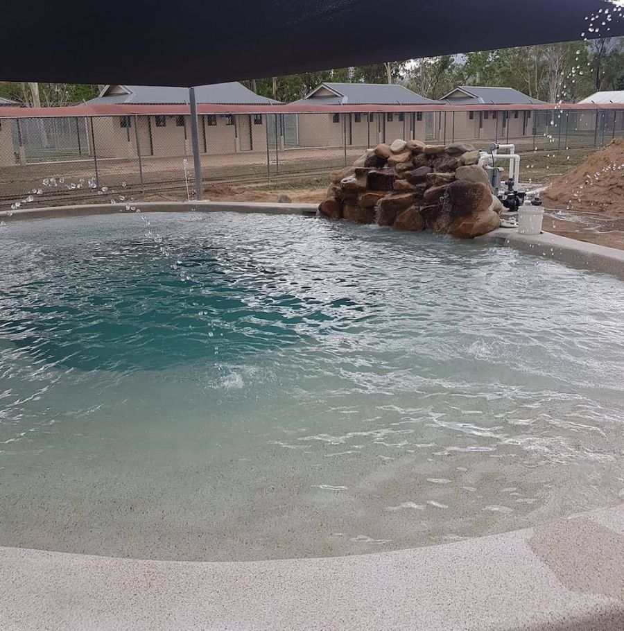 A Large Swimming Pool With a Large Rock in the Middle — NQ Tropical Pools & Renovations in Cranbrook, QLD