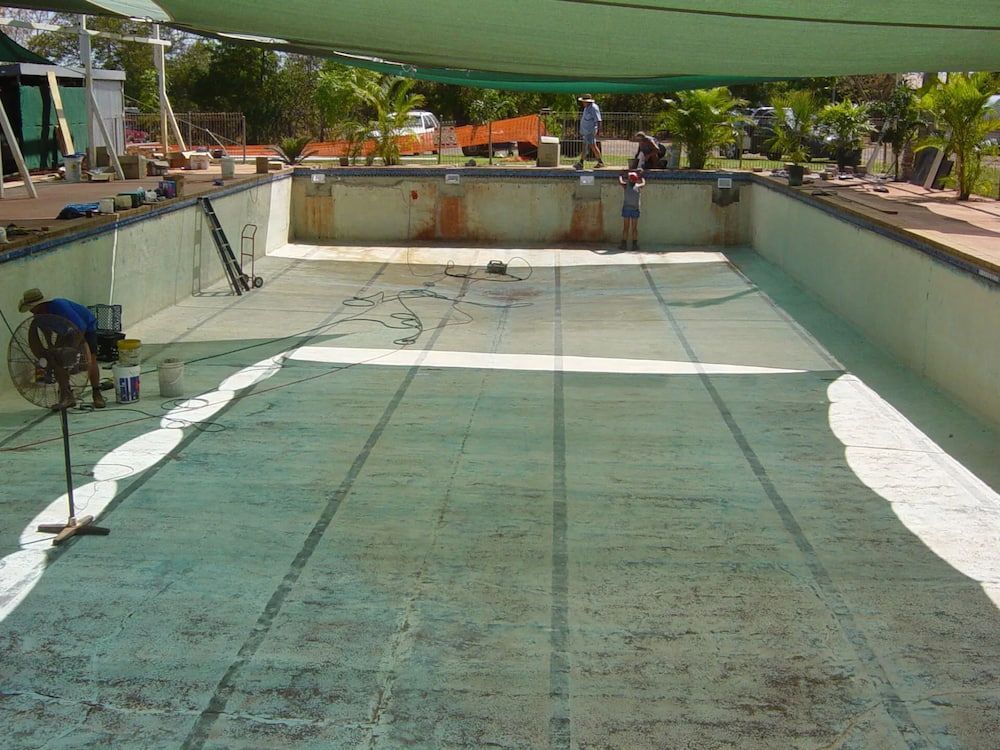 A Man is Cleaning the Floor of an Empty Swimming Pool — NQ Tropical Pools & Renovations in Cranbrook, QLD