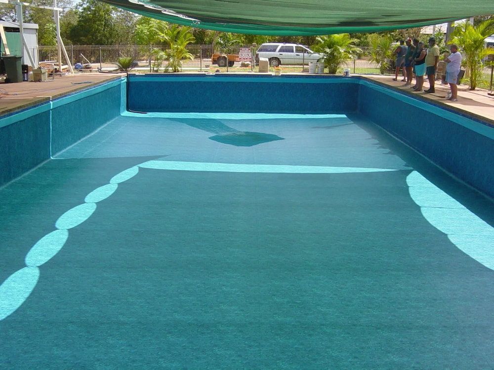 A Group of People Standing Around a Large Swimming Pool — NQ Tropical Pools & Renovations in Cranbrook, QLD
