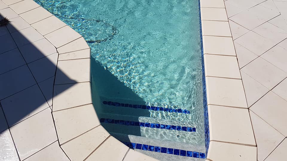 A Swimming Pool With Blue Tiles and a White Border — NQ Tropical Pools & Renovations in Cranbrook, QLD